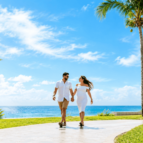 Couple walking hand in hand beside palm trees and the ocean